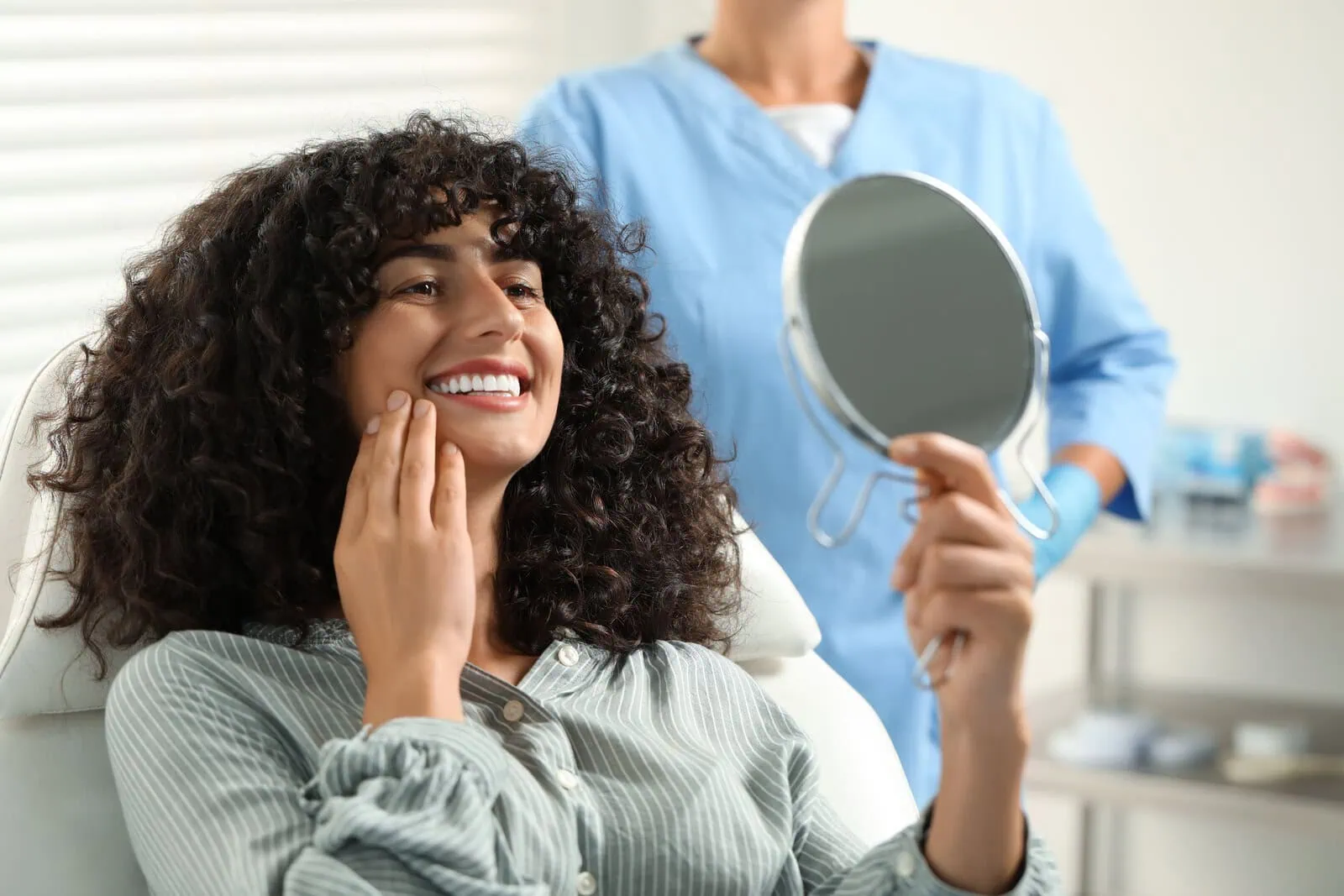 Patient admiring her smile in a hand mirror